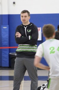 a man standing on the sidelines of a basketball court